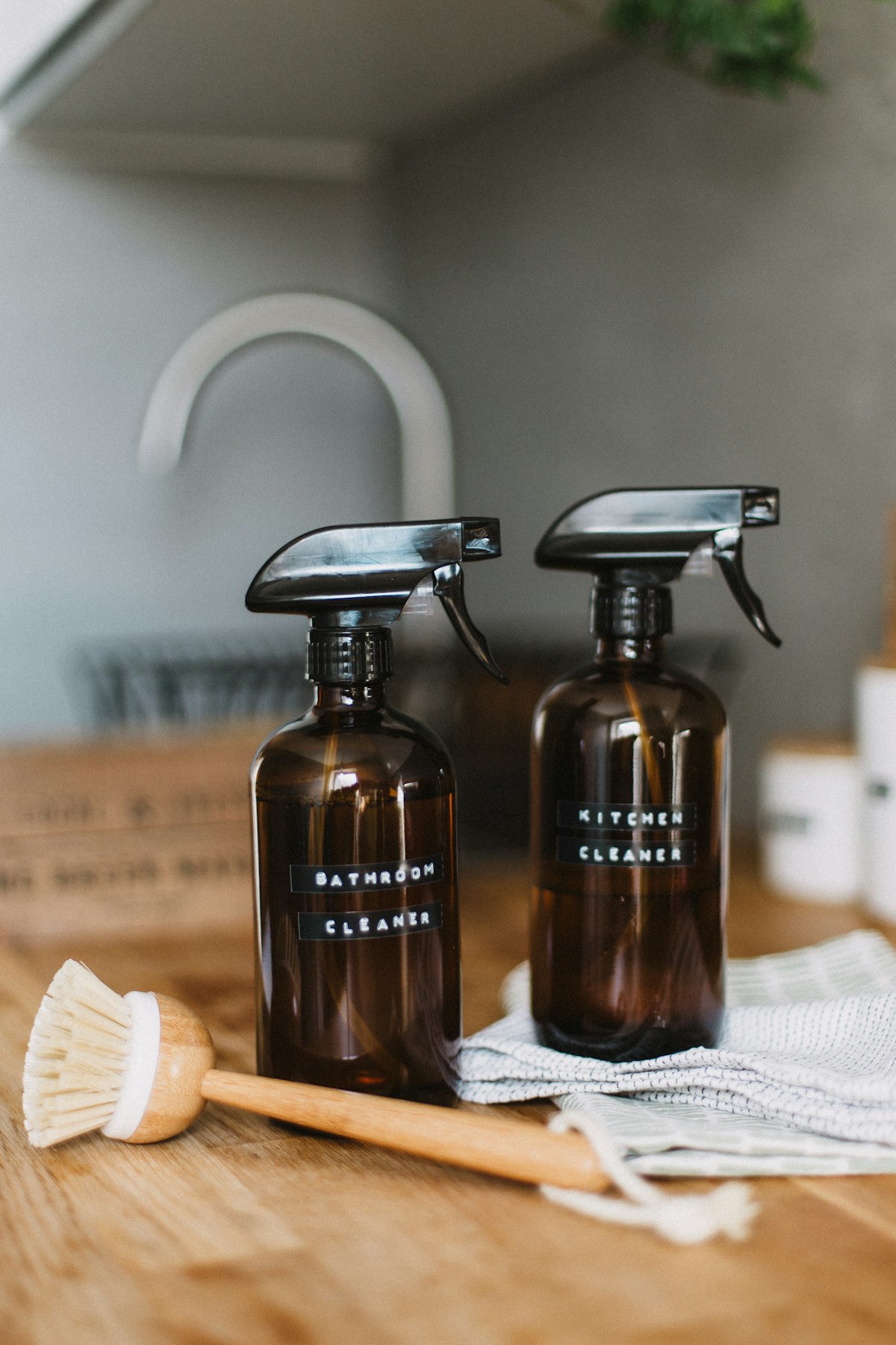 Eco-friendly cleaning bottles and brush on a wooden counter